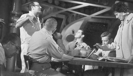 Irwin Allen discusses the upcoming take as a technician works foreground left and  script girl checks script.  Henry Kulk, Derrik Lewis and Richard Basehart seated.